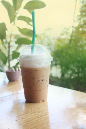 Closeup Plastic glass of iced coffee with milk on blurred background.の写真素材
