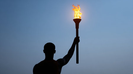 A powerful silhouette of a torchbearer holding a flaming torch against a dusky sky, representing hope, courage, and the spirit of perseverance in challenging times.の素材
