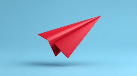 A vibrant red paper airplane floats against a soft blue background, embodying themes of freedom, creativity, and adventure, ideal for various design projects.の素材