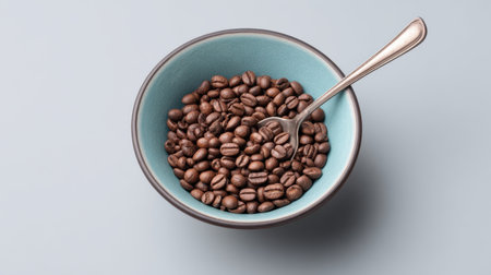 A bowl filled with freshly roasted coffee beans showcases a rich variety of textures and colors, accentuated by a silver spoon, perfect for culinary use.の素材