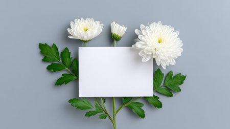 A stunning arrangement featuring elegant white flowers paired with a blank card on a soft gray background, perfect for creating personalized messages or invitations.の素材