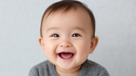 A captivating portrait of a cheerful baby displaying a joyful smile while wearing a cozy gray sweater. This image beautifully captures the essence of innocence and happiness, perfect for family-themed projects or childhood-related content.の素材