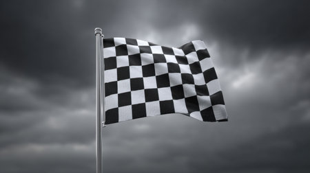 A striking black and white checkered flag flutters in the wind against a dark and stormy sky, symbolizing competition and victory in sports.の素材
