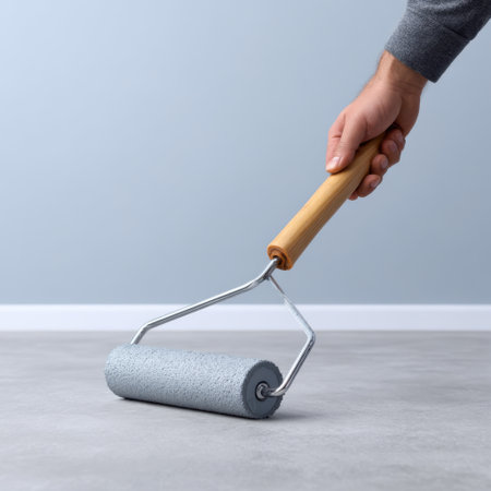A close-up view of a hand holding a paint roller against a freshly painted wall emphasizes the joy of creativity and home transformation.の素材