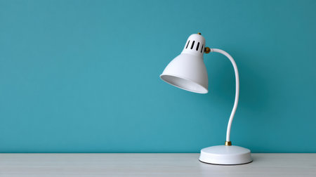 This image features a stylish white desk lamp with a sleek, minimalist design, complementing a trendy teal background, perfect for modern settings.の素材