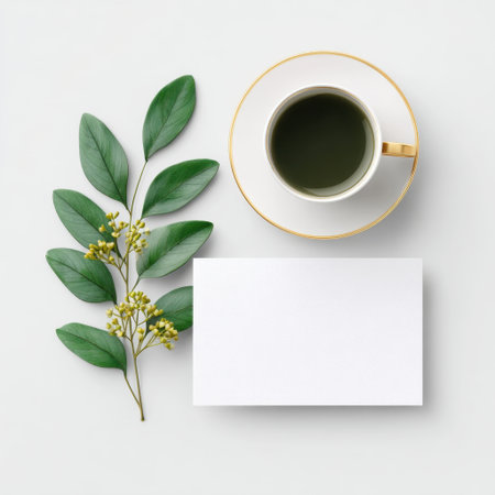 A serene composition featuring an elegant tea cup surrounded by greenery and a blank card, perfect for artistic and lifestyle themes in design projects.の素材