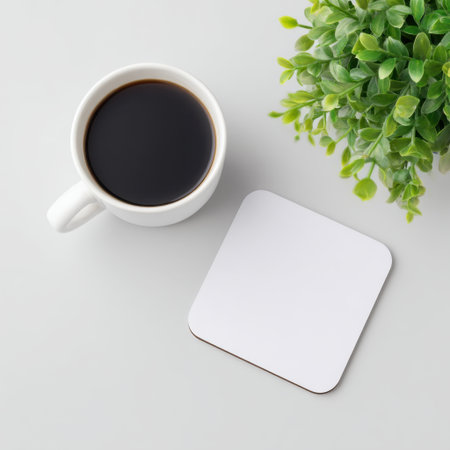 A serene scene featuring a coffee cup, a green plant, and a simple coaster on a clean table. This minimalistic arrangement creates a peaceful atmosphere perfect for relaxation and focus.の素材