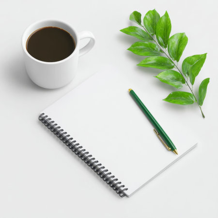 A tranquil and minimalist workspace featuring a cup of coffee, a blank notebook, and a green pen alongside vibrant leaves, perfect for creative moments.の素材