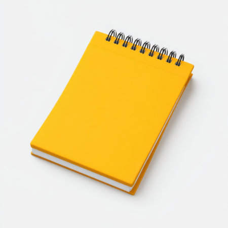 A vibrant yellow spiral notebook resting on a clean white background, perfect for showcasing stationery concepts, office supplies, or creative projects.の素材