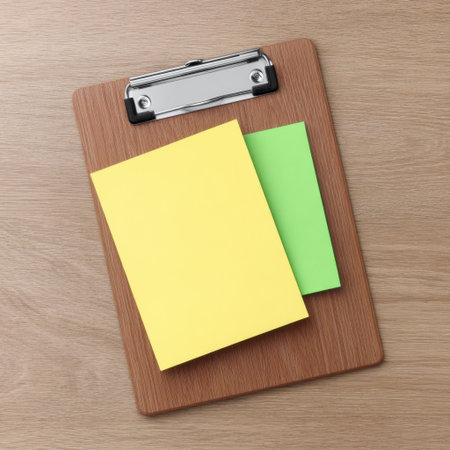 Bright and colorful sticky notes in yellow and green are arranged neatly on a wooden clipboard, perfect for creative organization and planning in an office or home workspace.の素材