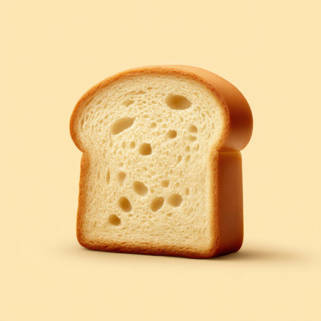 A single slice of white bread with a golden brown crust sits on a soft yellow background, showcasing its airy texture and inviting appearance.の素材