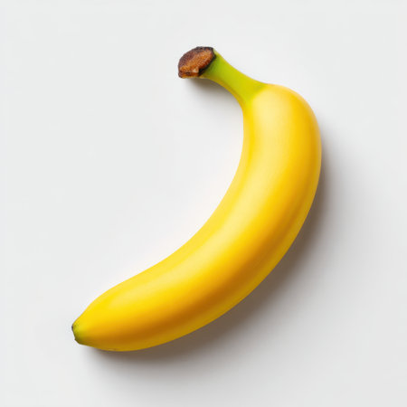 A vibrant yellow banana rests on a clean white background, showcasing its smooth texture and natural beauty. Perfect for health and nutrition themes.の素材