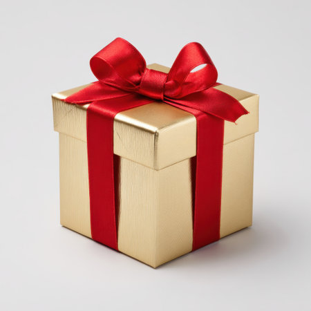 This elegant gold gift box, adorned with a striking red ribbon, is perfect for any festive occasion, adding a touch of luxury and charm.の素材