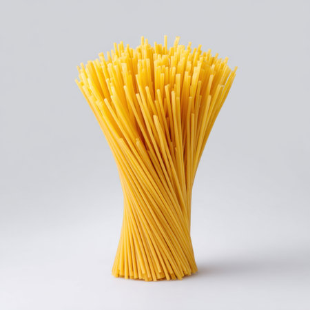 Aesthetic arrangement of yellow dry pasta sticks standing upright, ideal for showcasing culinary creativity and vibrant food presentations in cooking.の素材