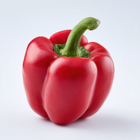 A fresh red bell pepper stands with a glossy finish on a clean white background, showcasing its vibrant color and healthy appeal for food enthusiasts.の素材