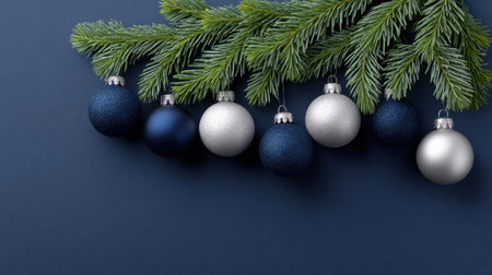 Beautifully arranged Christmas ornaments in silver and blue hang from lush green pine branches on a dark background, evoking festive joy and elegance.の素材