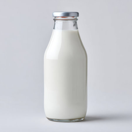 A classic glass bottle filled with fresh milk stands against a smooth gray background, embodying freshness and simplicity, perfect for culinary uses.の素材