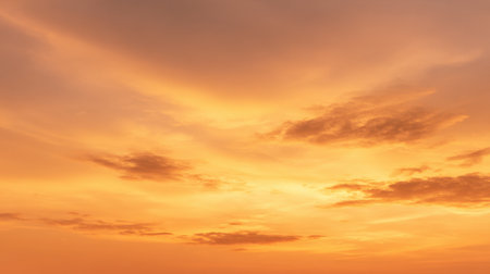 Experience the breathtaking beauty of a sunset sky filled with warm orange tones and soft, billowing clouds, perfect for serene landscapes.の素材