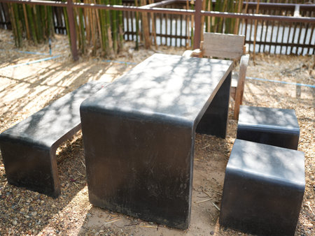 A minimalist outdoor furniture set featuring a smooth table and stools situated in a natural setting with bamboo fencing, perfect for relaxation and gatherings.の写真素材