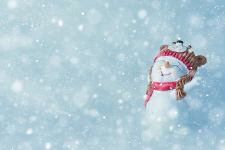 Merry christmas and happy new year greeting card with happy snowman standing in winter christmas landscape.