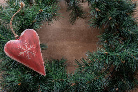 Christmas decoration heart on the green fir branches. Christmas time background.