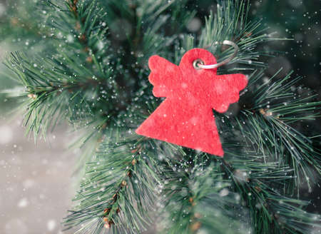 Red angel keychain on fir brunches. Winter time concept.の写真素材