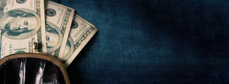 Black small vintage open wallet with roll of dollars on a blue jeans background. Copy space.の写真素材