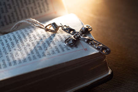 Closeup of beautiful Christian cross on a pray book on the old table. Church utensils.