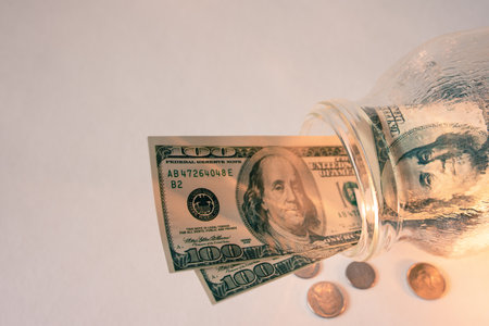 Saving money concept. Dollar bills in glass jar on the white table.の写真素材