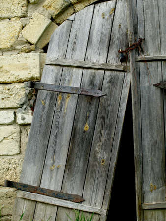 Old stone entrance with a broken wooden doorの写真素材