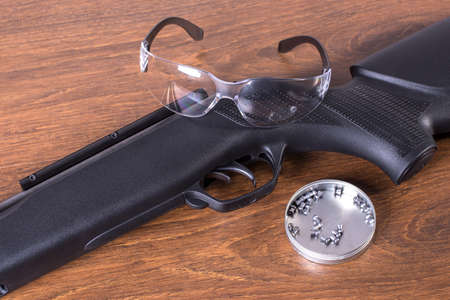 Air rifle with safety glasses and bullets on wood texture backgroundの写真素材