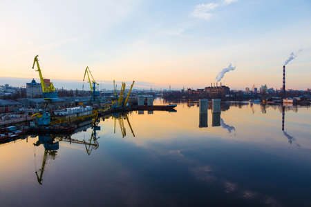 Trade dock cranes reflected in the mirrored surface of the river at sunsetのeditorial素材