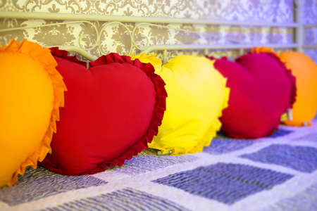Pillows in the shape of hearts lie on the couch in a row