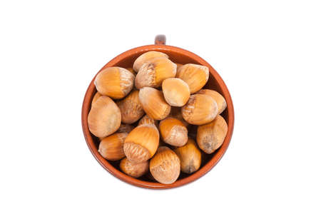 Ceramic pot full of hazelnut heap isolated on white