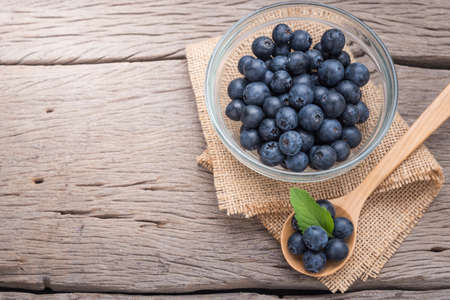 blueberries in wooden spoon and  glass cup on wood background.の写真素材