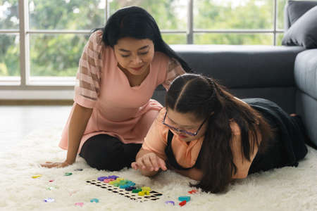 young girl is having fun practicing and learning with toys at home with her mother to develop her skillsの写真素材