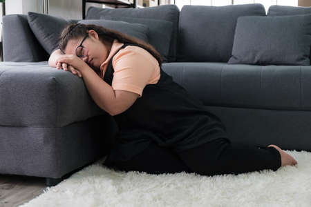 A lonely child Asian autistic girl sits on the sofa to feel lonely at home during the COVID-19 epidemic.の写真素材