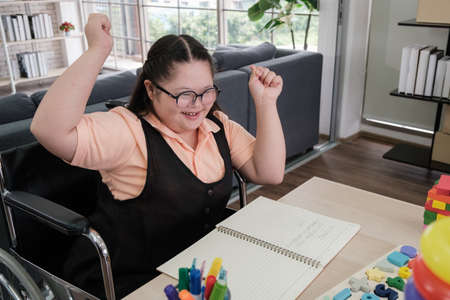 young girl on wheelchair is practicing writing and learning with toys at home to develop her skills.の写真素材