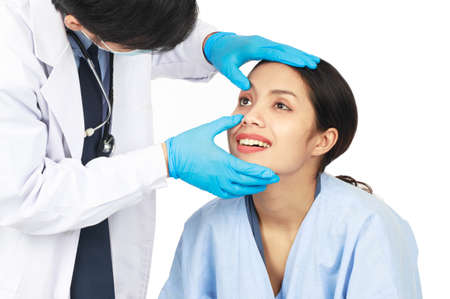 A male doctor examining the eyes of a young patient  on white background. Healthcare and medical concept.の写真素材