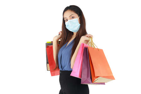 Isolated beautiful woman holding paper shopping bags and wearing mask protect coronavirus in a new normal on white background.の写真素材