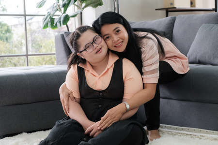 Asian mother hugging young girl while smiling and looking at cameraの写真素材