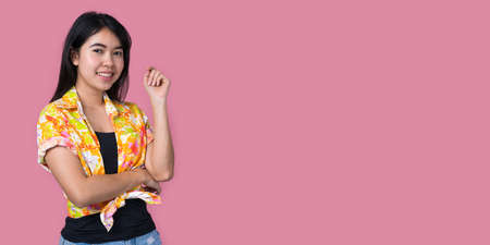 Portrait of a beautiful Asian woman wearing yellow Hawaiian shirt with a pink background.  Summer conceptの写真素材