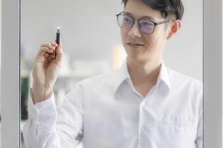 A businessman planning a marketing plan with his team. Professional teachers write on the glass...