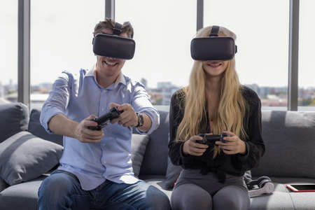 Young couple sitting on the floor at home. Portrait of wife and husband have fun playing video games...