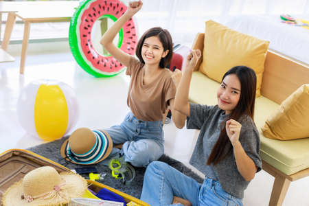 Two young Asian women are planning a summer vacation and are having fun in their bedrooms. concept of travel in summer and holiday.の写真素材