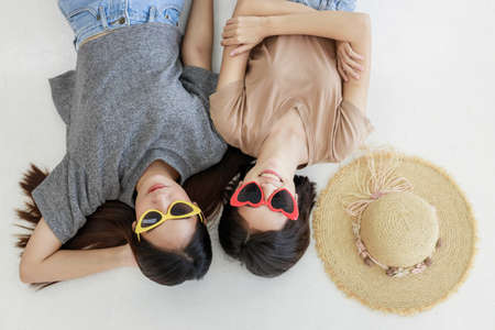 Portrait of two young asian woman in summer concept smiling  and lying on white floor.の写真素材