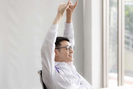 Portrait of young Asian doctor wearing glasses is relaxing and smiling in the room at hospital. health care and medical concept.の写真素材