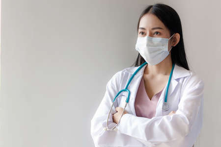 Portrait of young Asian female doctor wearing a mask with stethoscope on white background. healthcar...