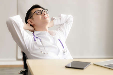 Portrait of young Asian doctor wearing glasses is relaxing and smiling in the room at hospital. health care and medical concept.の写真素材