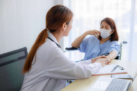 Friendly Asian female doctor's hands holding female patient's hand for encouragement and empathy. Medical psychology in encouraging and reducing the negative effects of sick people.の写真素材